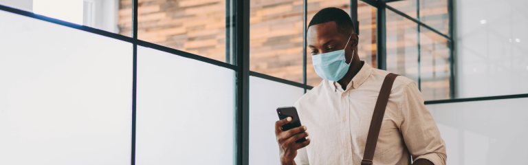 A man wearing a mask and holding mobile phone