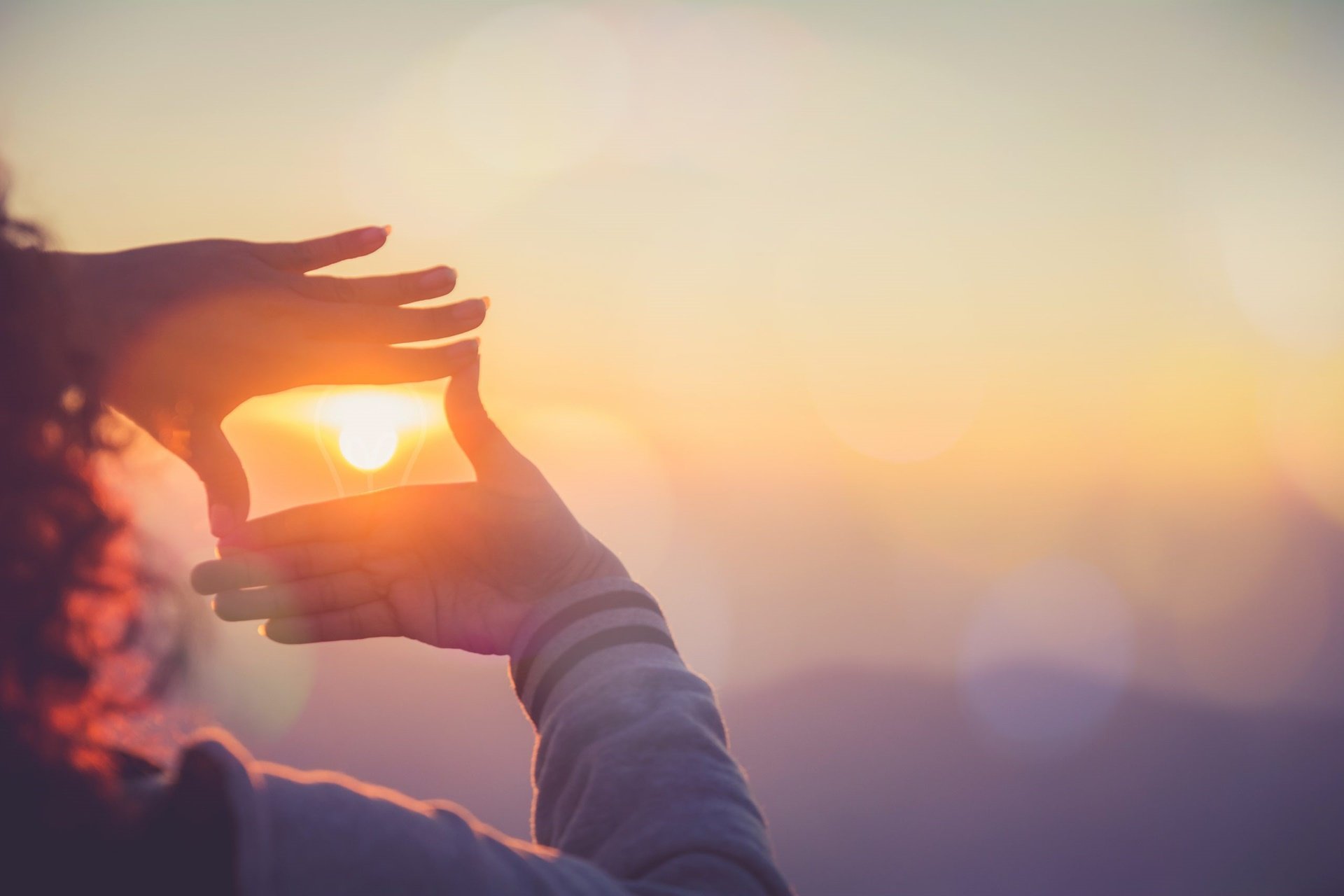 A woman cropping the sun with her hands