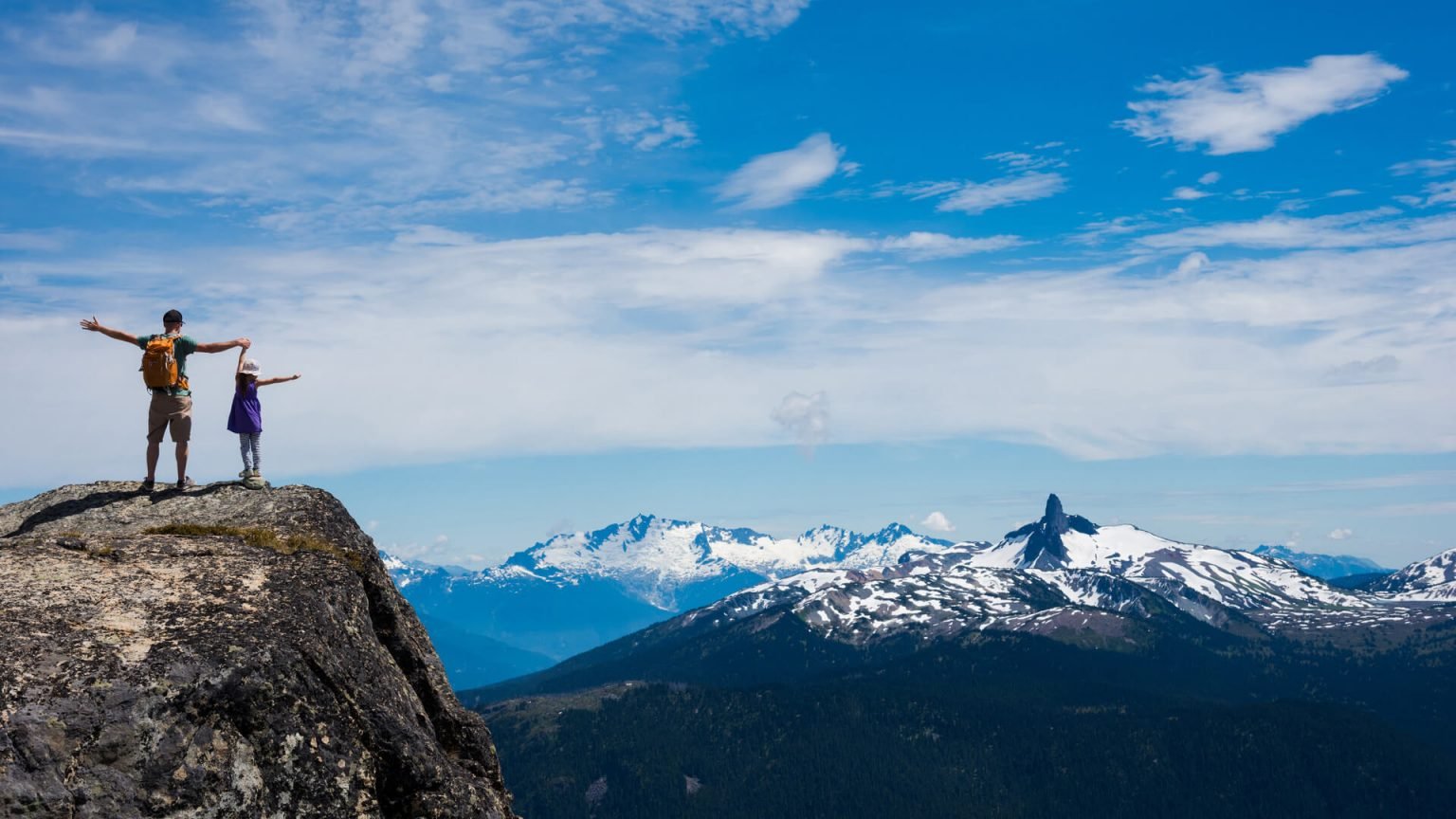 Father and daughter enjoying a stunning mountain backdrop