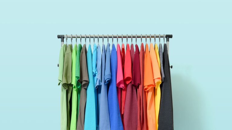 Mobile rack with color clothes on light blue background