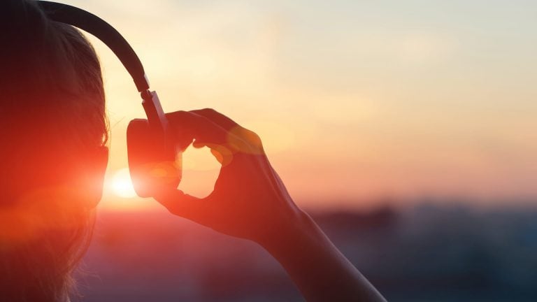 Person holding headphones at sunset
