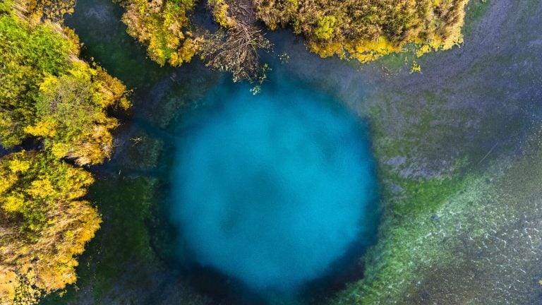 Aerial view of a small round karst lake