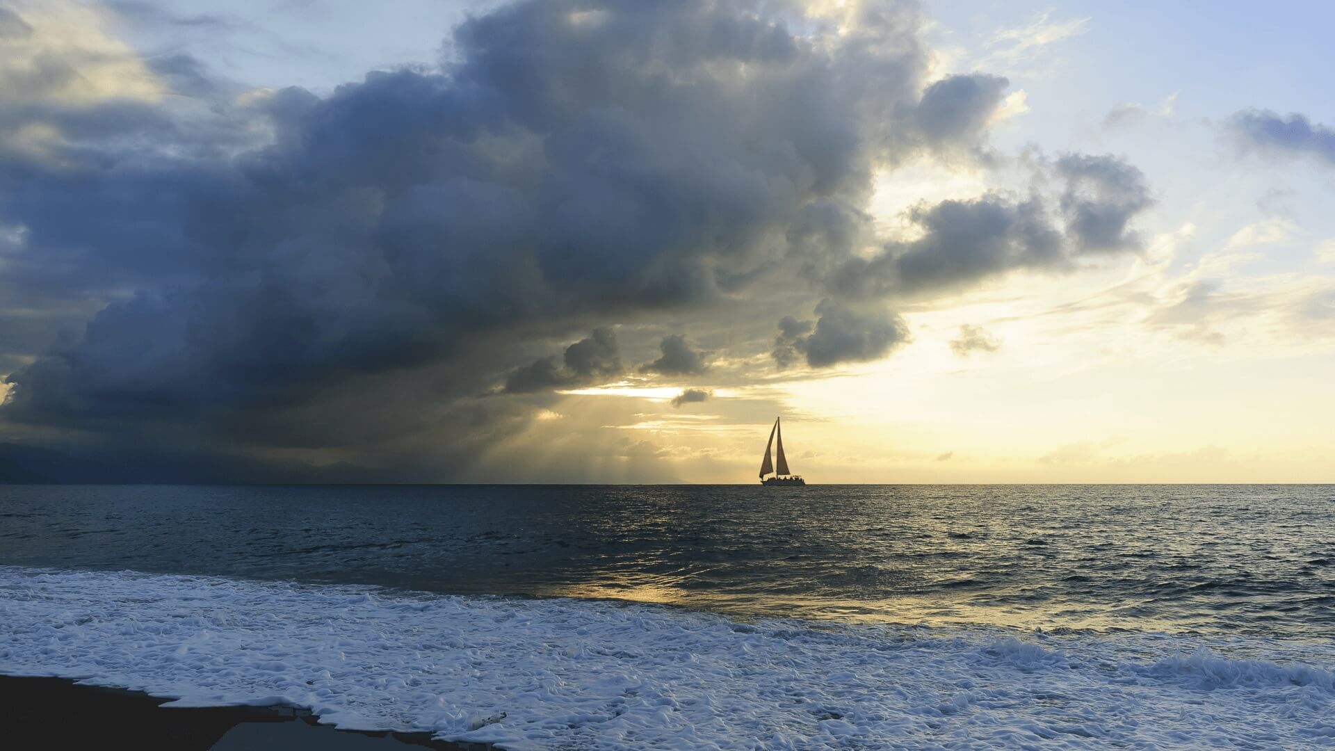 Sailing boat at the sea against the background of the cloudy sky
