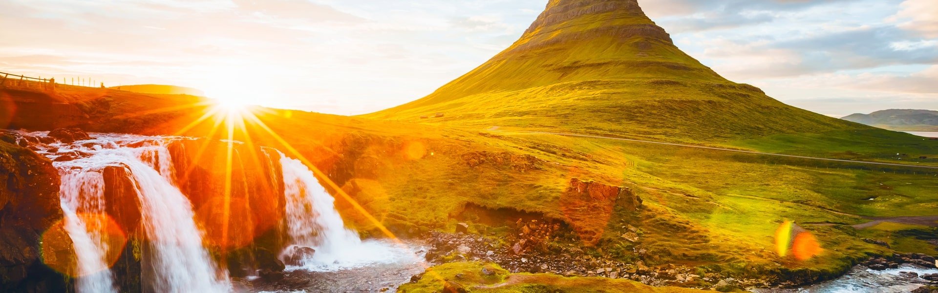 Waterfall with mountains in the background at sunset