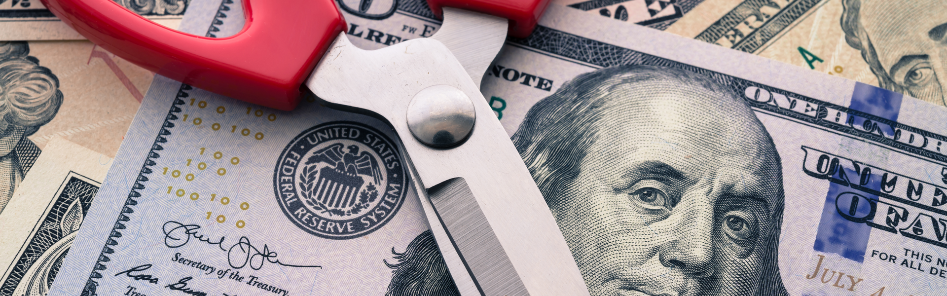 scissors on top of a $100 bill