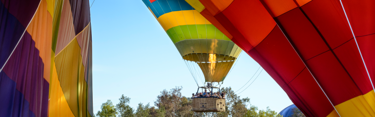 three hot air balloons, one with a basket of passengers