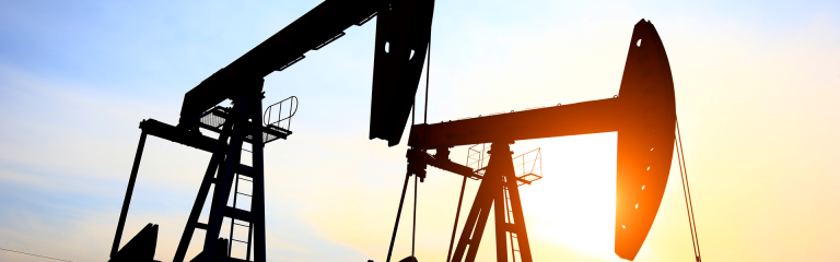 two oil pumps against a setting sun
