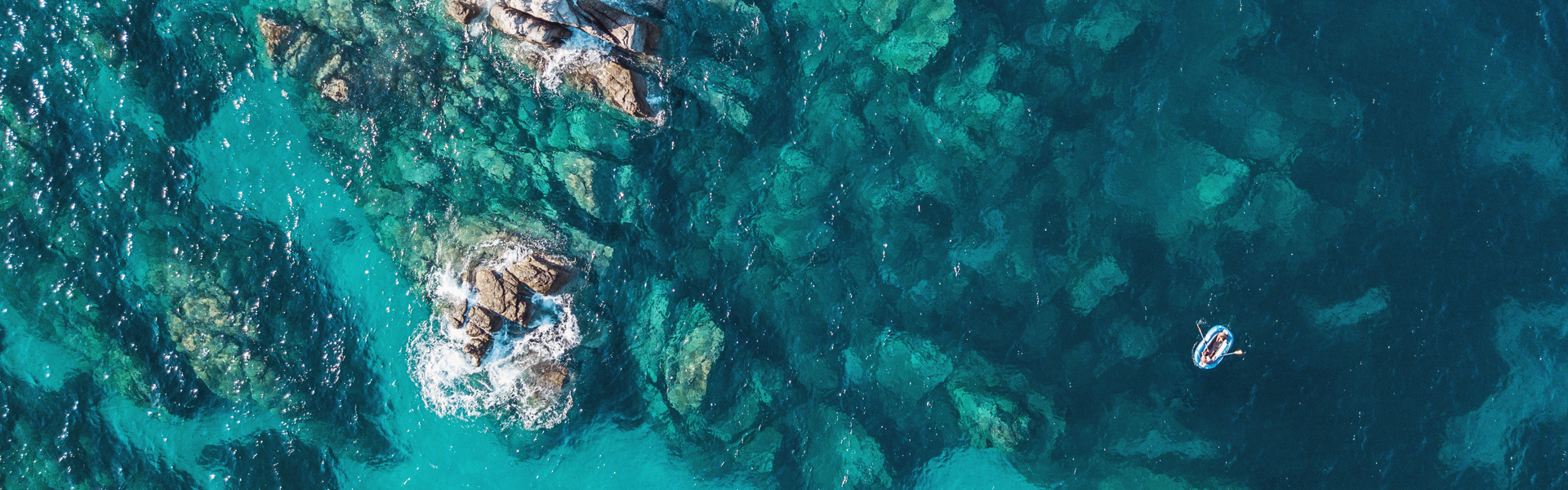rocky bay, viewed from above, with a lone dingy boat