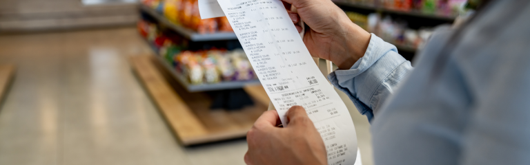 a woman is standing in a supermarket and reading her receipt