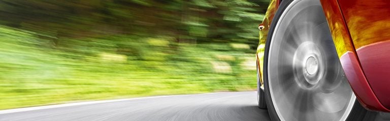 Wheel of a red car taking a corner at speed.