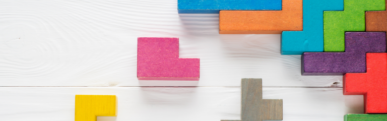 multi-coloured wooden blocks on white wooden background, in tetris formation