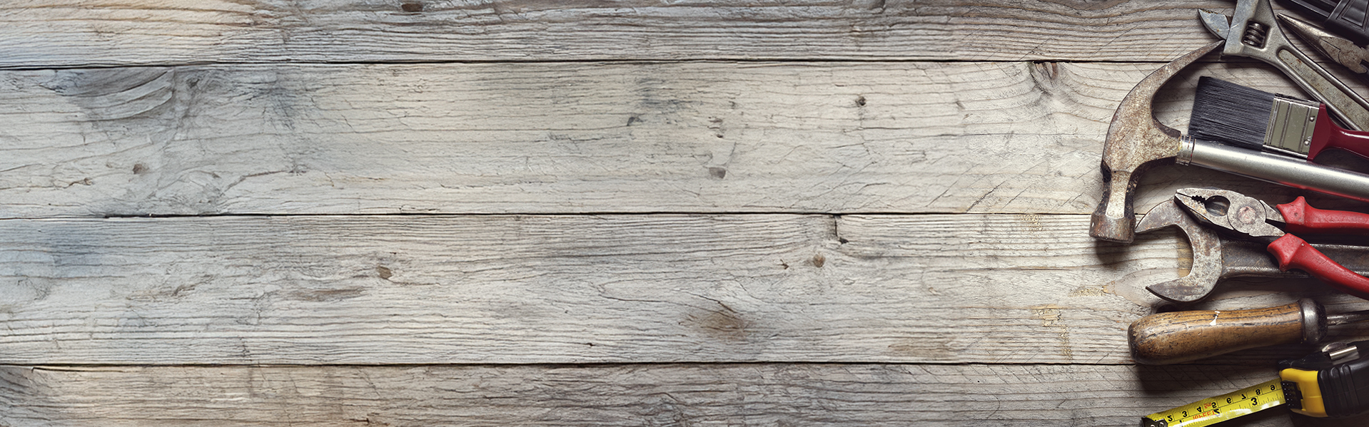 Hammer, screwdriver, wrench, tape measure, construction tools on wooden bench