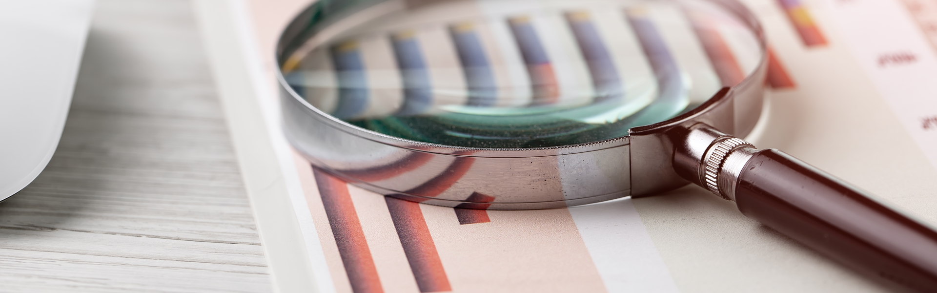 magnifying glass on top of paper with graphs