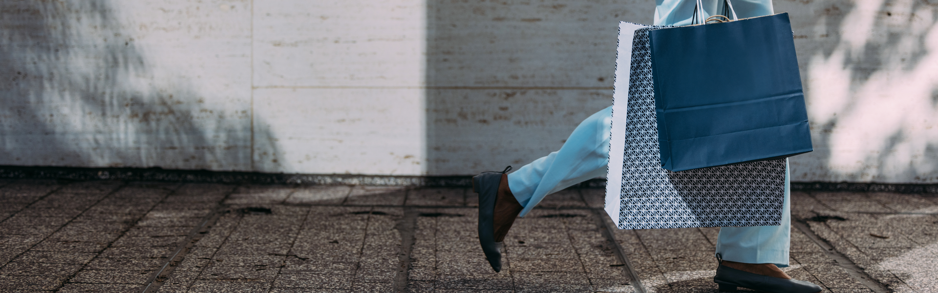 a woman is walking down the street with several bags in her right hand