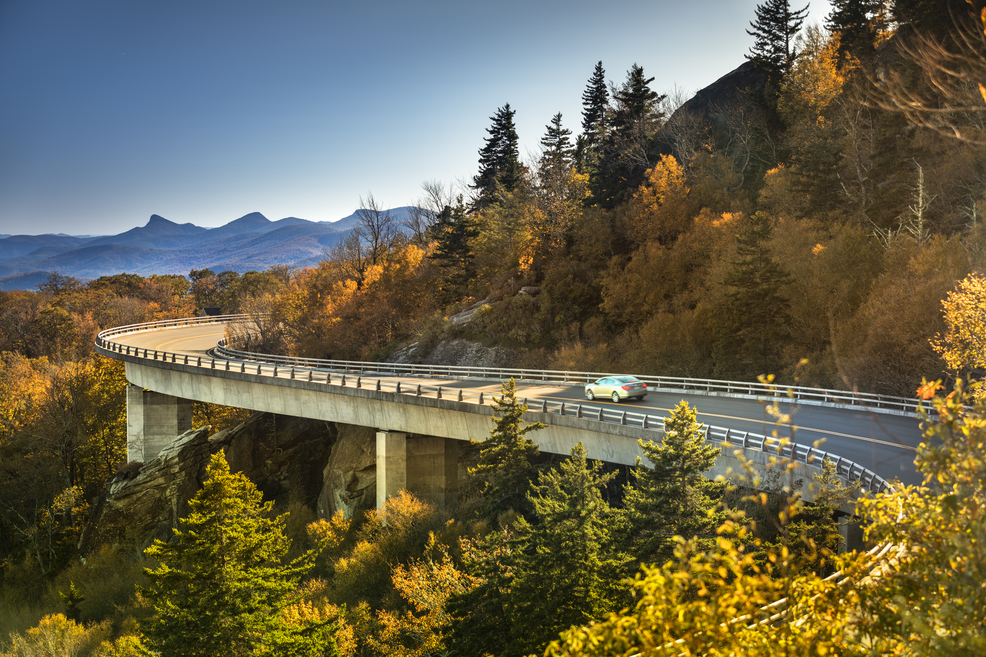 a view of a car going over a bridge in the mountains