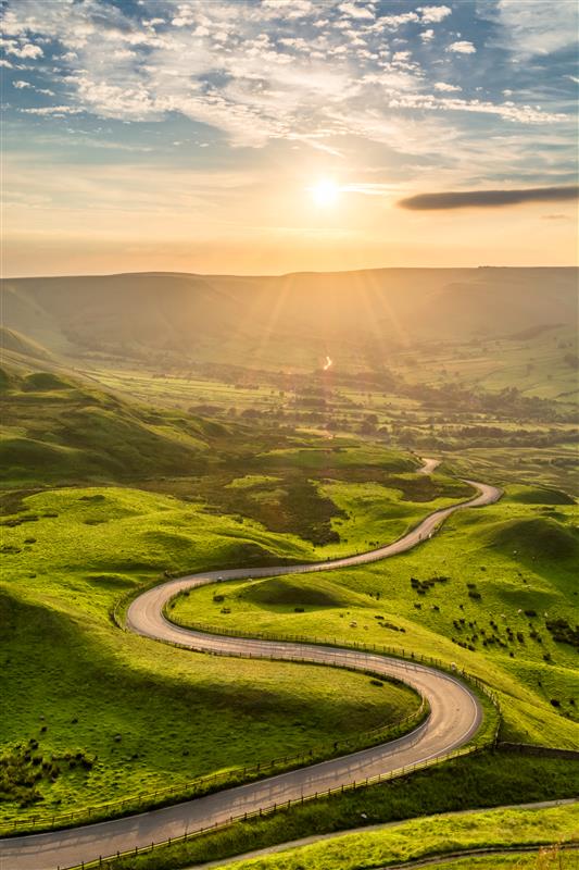 a road leading into the distance against a setting sun