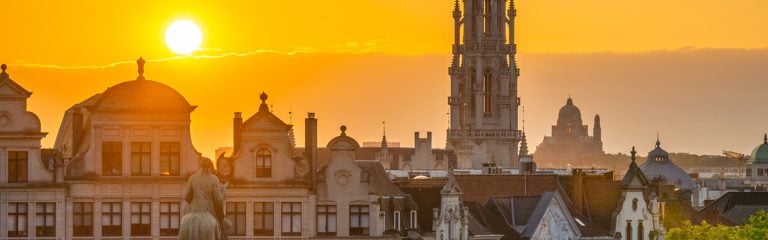 Sunset over gabled house rooftops in the Low Countries, with cropped view of Northern Renaissance bell tower.