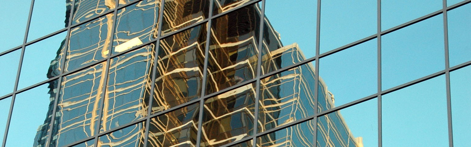 Reflection of skyscraper in glass windows banner image
