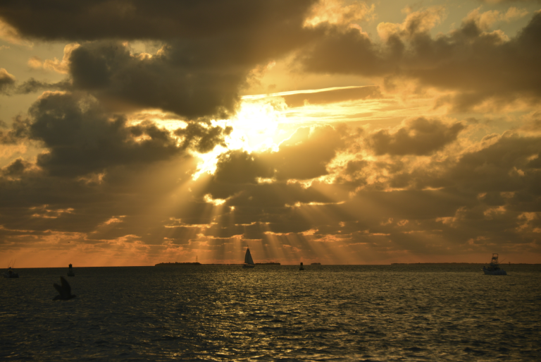 Image of a sunset over the ocean, obscured by clouds.